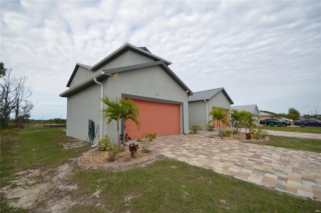 view of property exterior with an attached garage, a lawn, driveway, and stucco siding