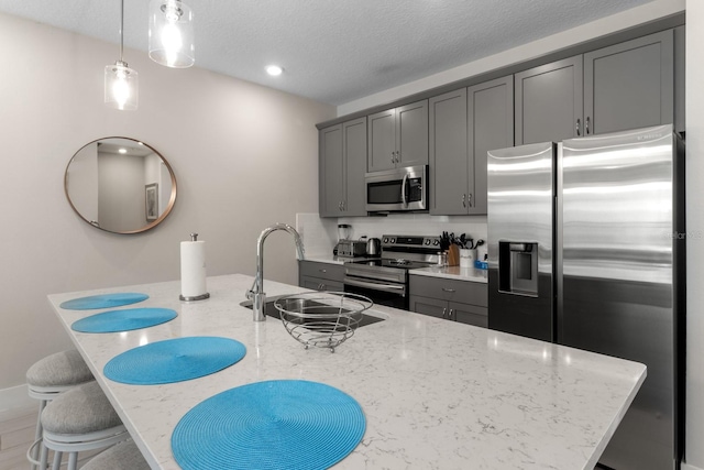 kitchen with sink, gray cabinets, tasteful backsplash, light stone counters, and stainless steel appliances