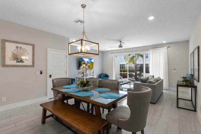 dining space with ceiling fan with notable chandelier and light hardwood / wood-style flooring