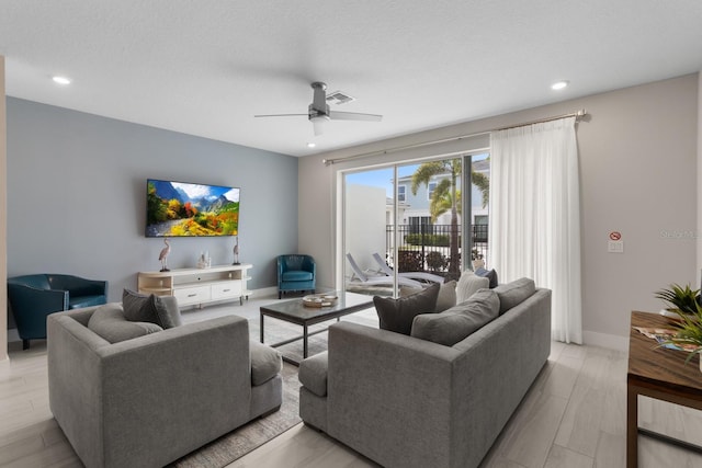 living room featuring a textured ceiling, light hardwood / wood-style flooring, and ceiling fan