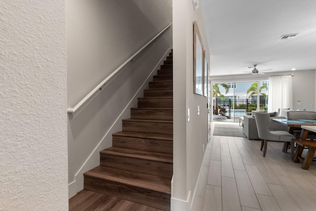 stairs featuring ceiling fan and hardwood / wood-style floors