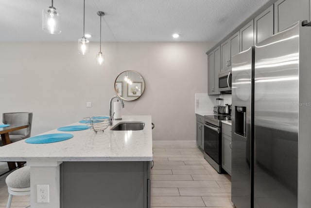 kitchen with backsplash, light stone counters, stainless steel appliances, sink, and hanging light fixtures