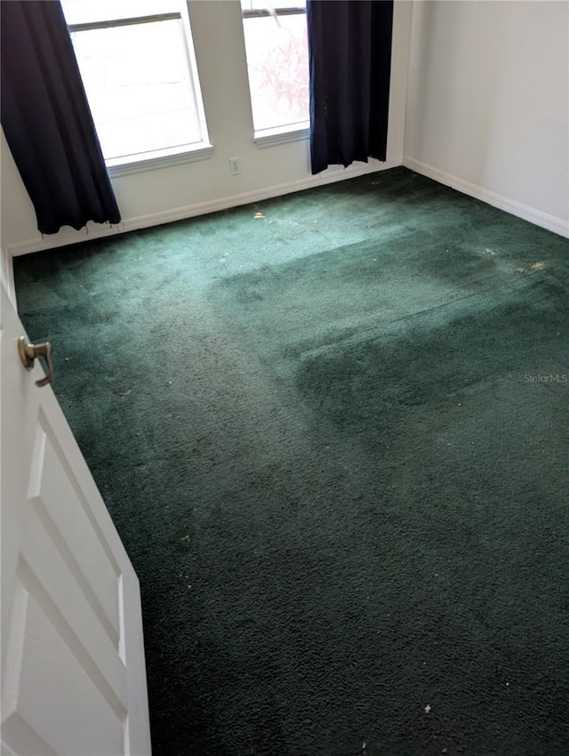 empty room with dark colored carpet and baseboards