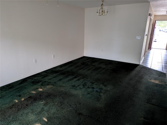 empty room featuring baseboards, carpet, and an inviting chandelier