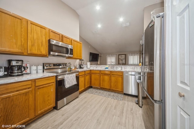 kitchen featuring kitchen peninsula, light wood-type flooring, stainless steel appliances, vaulted ceiling, and sink