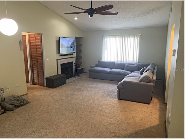 living room with a tiled fireplace, ceiling fan, carpet floors, high vaulted ceiling, and a textured ceiling