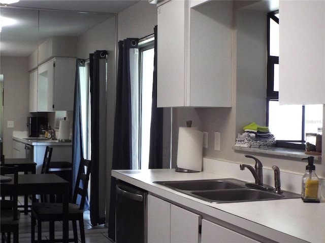 kitchen featuring dishwasher, white cabinets, and sink