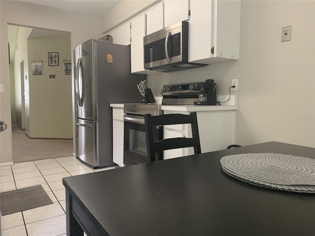 kitchen with light carpet, white cabinets, and stainless steel appliances