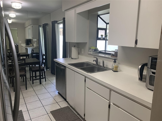 kitchen featuring sink, white cabinets, light tile floors, and stainless steel appliances