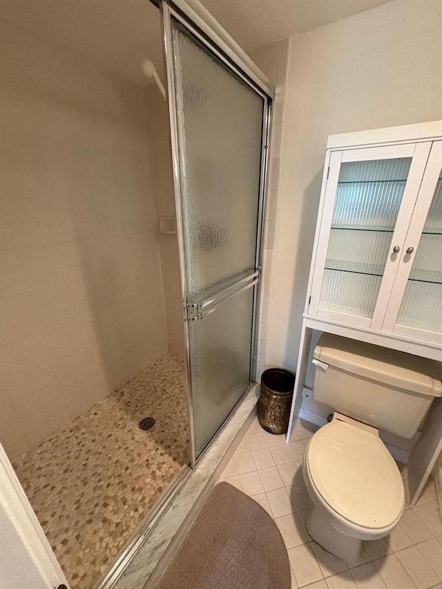 bathroom with tile patterned flooring, a shower with door, and toilet