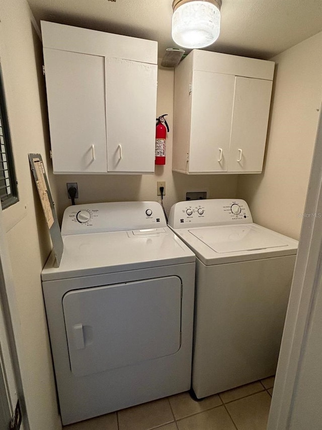 washroom with cabinets, washer and dryer, and light tile patterned floors