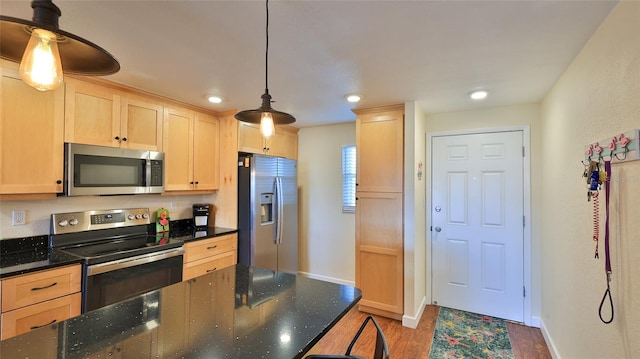 kitchen featuring hanging light fixtures, light brown cabinetry, stainless steel appliances, and dark hardwood / wood-style floors