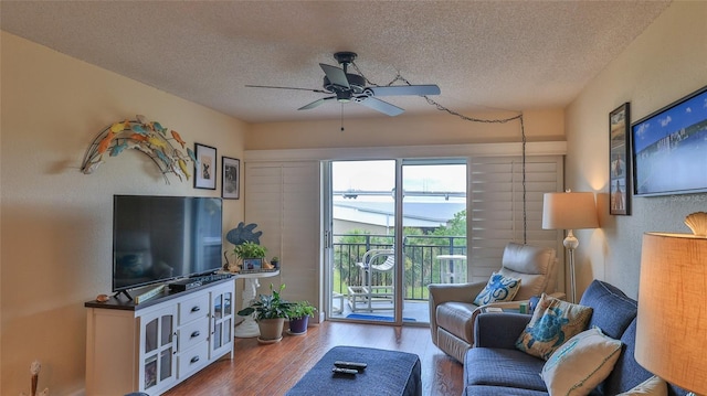 living room featuring ceiling fan, a textured ceiling, and hardwood / wood-style flooring