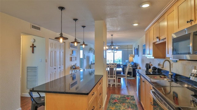 kitchen with stainless steel appliances, an inviting chandelier, dark hardwood / wood-style flooring, pendant lighting, and a kitchen island