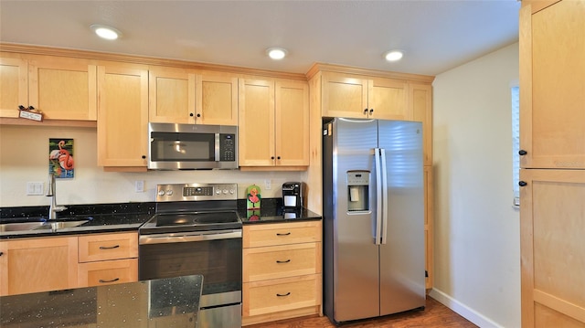 kitchen with appliances with stainless steel finishes, light brown cabinets, hardwood / wood-style flooring, and sink