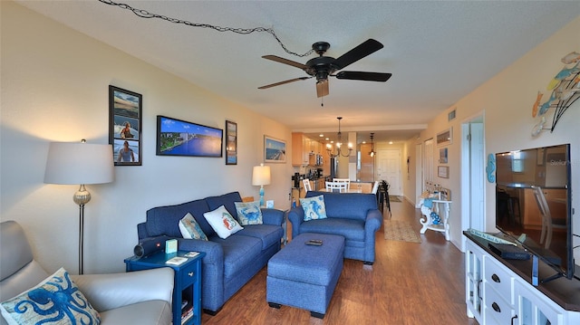 living room featuring ceiling fan with notable chandelier and dark hardwood / wood-style floors