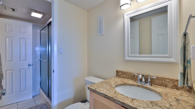 bathroom featuring tile patterned floors, vanity, toilet, and a shower with shower door