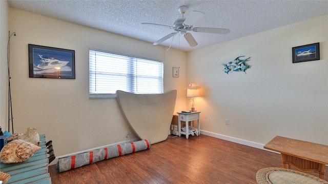 sitting room featuring a textured ceiling, ceiling fan, and dark wood-type flooring