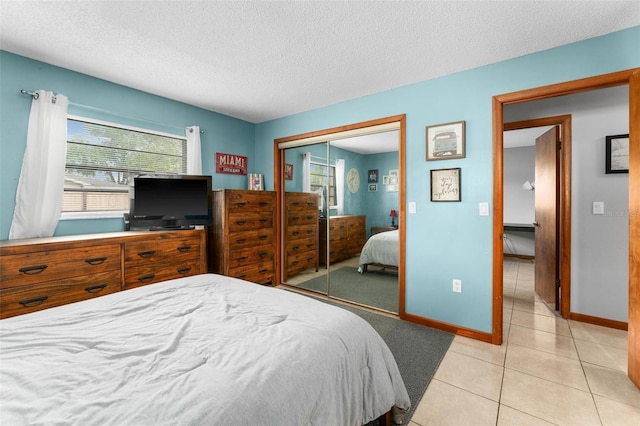 bedroom featuring light tile patterned floors, a textured ceiling, and a closet