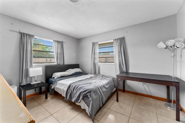 bedroom featuring a textured ceiling, multiple windows, and light tile patterned flooring