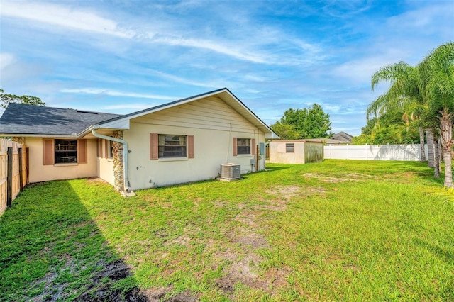 back of property featuring central air condition unit, a yard, and a storage unit