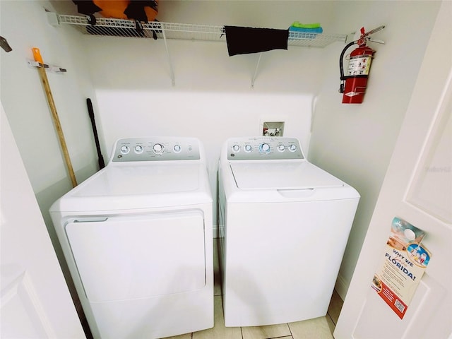 laundry room with independent washer and dryer and light tile patterned flooring