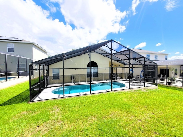 view of pool with glass enclosure, a patio area, and a yard