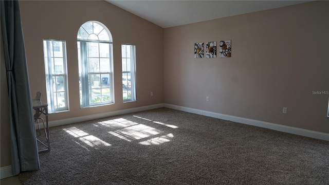 carpeted spare room with vaulted ceiling and a healthy amount of sunlight