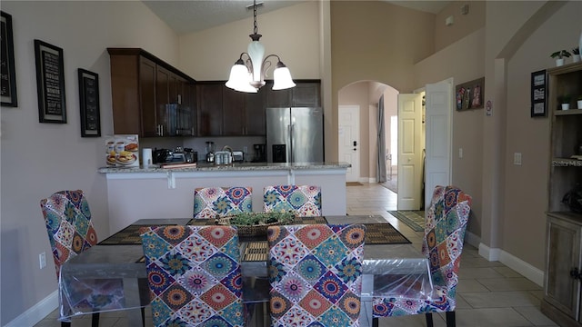 dining room featuring lofted ceiling, light tile patterned flooring, and an inviting chandelier