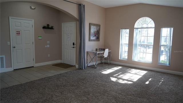 entrance foyer with vaulted ceiling and light colored carpet