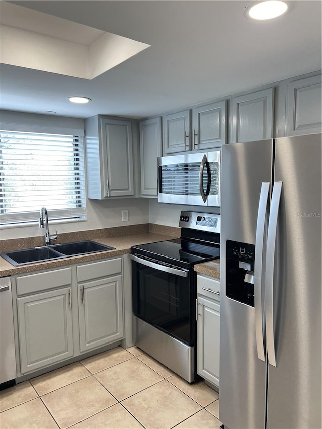 kitchen featuring stainless steel appliances, sink, and light tile floors