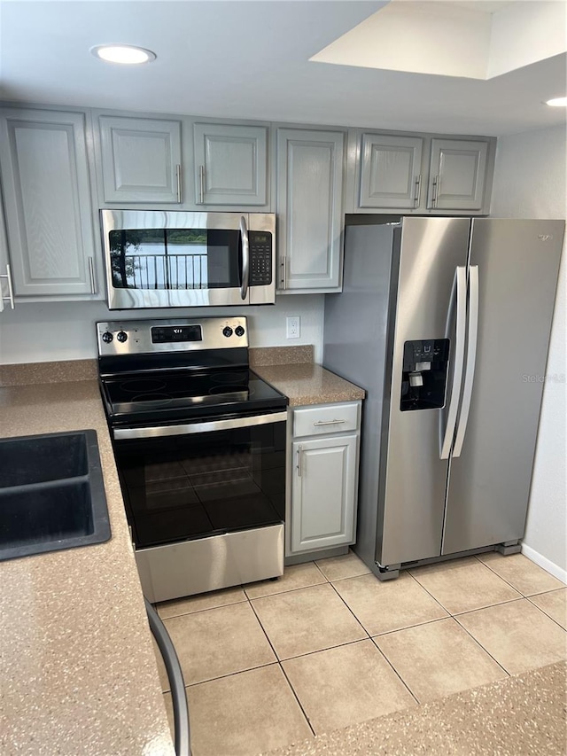 kitchen featuring appliances with stainless steel finishes, gray cabinets, and light tile floors