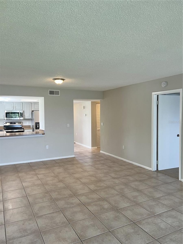 unfurnished living room featuring a textured ceiling and light tile flooring