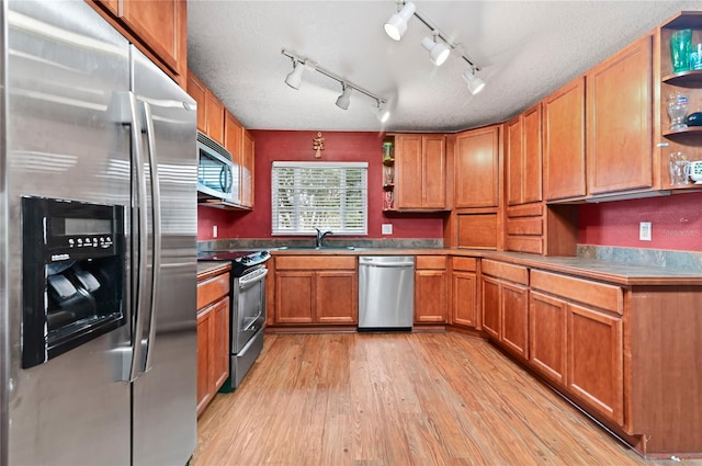 kitchen with light hardwood / wood-style flooring, a textured ceiling, track lighting, sink, and appliances with stainless steel finishes