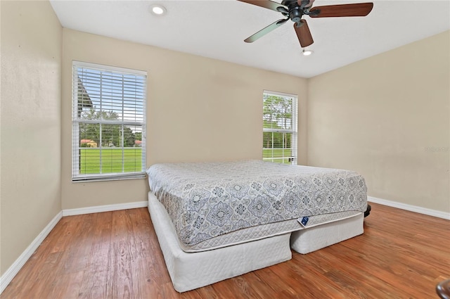 bedroom with hardwood / wood-style floors, ceiling fan, and multiple windows