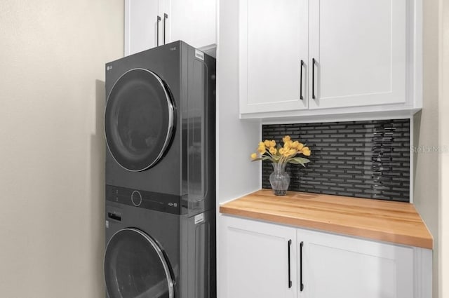 clothes washing area with cabinets and stacked washer and clothes dryer