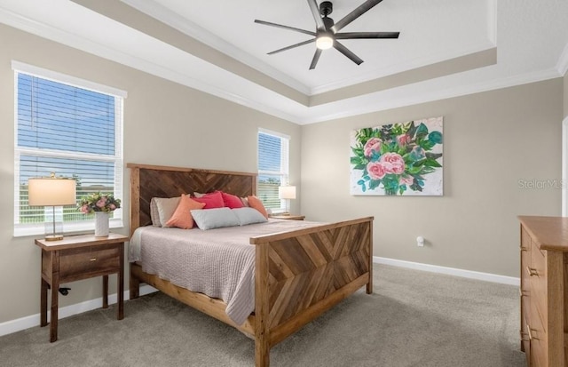 carpeted bedroom with ceiling fan, ornamental molding, and a tray ceiling