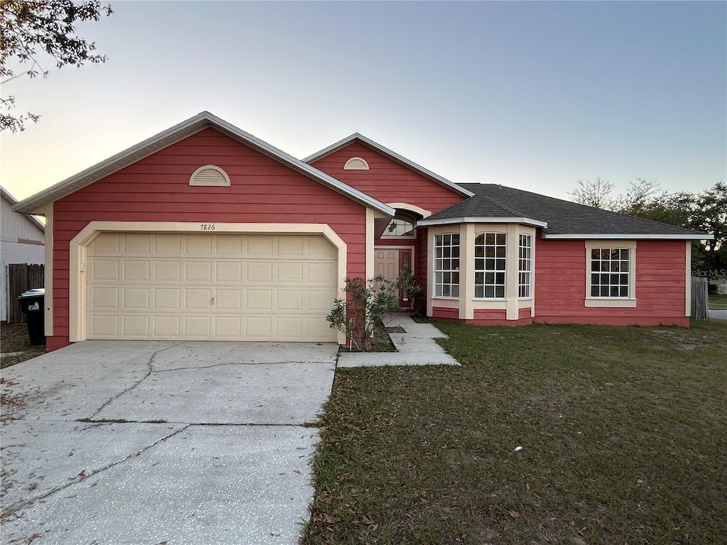 single story home featuring a garage and a lawn