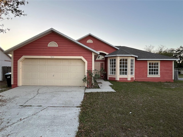 single story home featuring a garage and a lawn