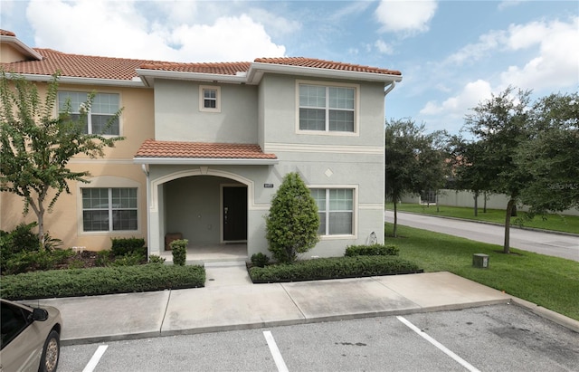 view of front of house featuring covered porch, a tile roof, uncovered parking, stucco siding, and a front lawn