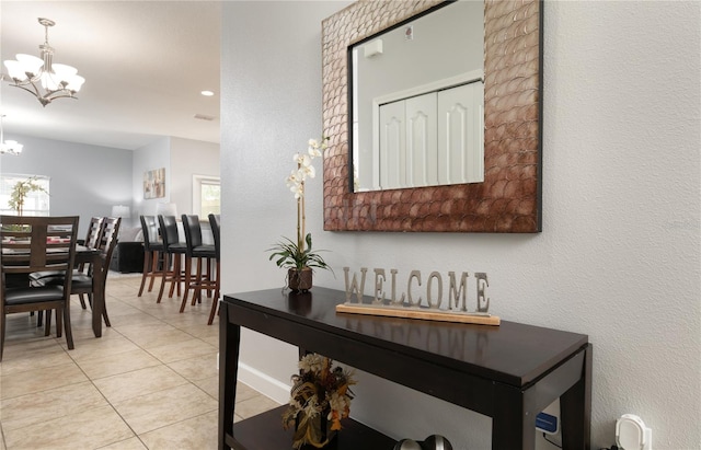 hall with light tile patterned floors, an inviting chandelier, and plenty of natural light