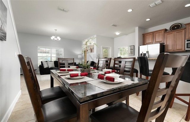 dining area with plenty of natural light, light tile floors, and an inviting chandelier