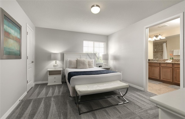 carpeted bedroom featuring baseboards, ensuite bathroom, and a textured ceiling