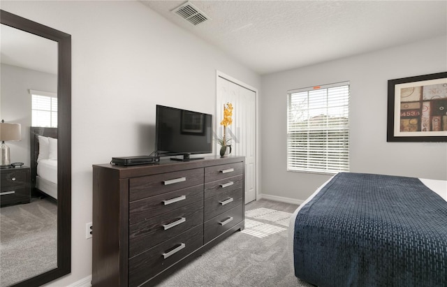 carpeted bedroom featuring a textured ceiling, baseboards, visible vents, and multiple windows