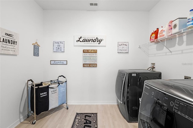 laundry room featuring laundry area, baseboards, visible vents, washing machine and clothes dryer, and light wood-type flooring