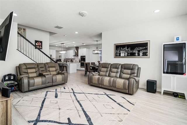 living room featuring light wood-type flooring, stairs, a notable chandelier, and recessed lighting