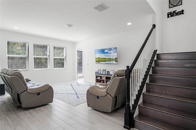 living room featuring light wood-style flooring, recessed lighting, visible vents, and stairway