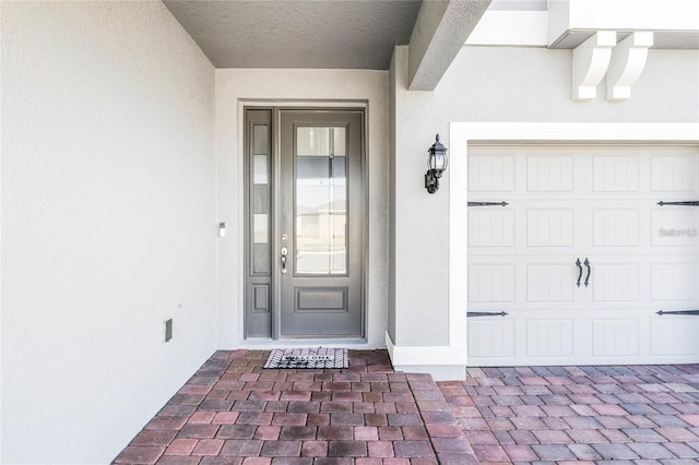 doorway to property with a garage and stucco siding