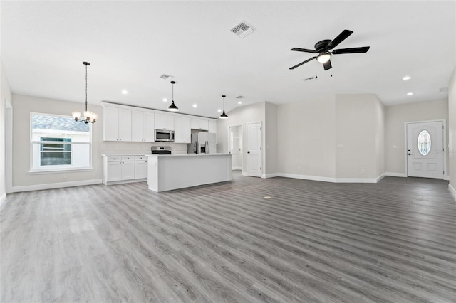 unfurnished living room with ceiling fan with notable chandelier and light hardwood / wood-style flooring