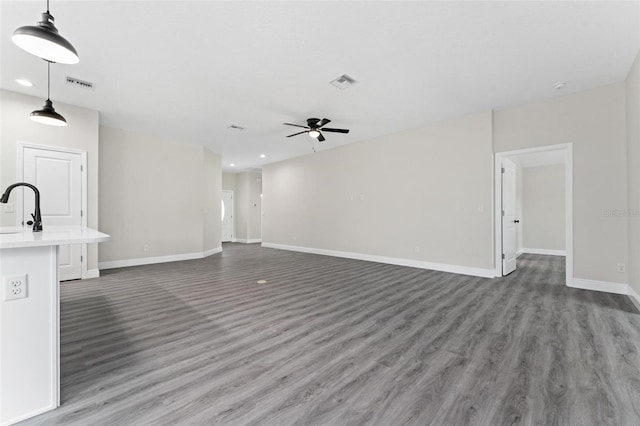 unfurnished living room featuring sink, ceiling fan, and dark hardwood / wood-style floors